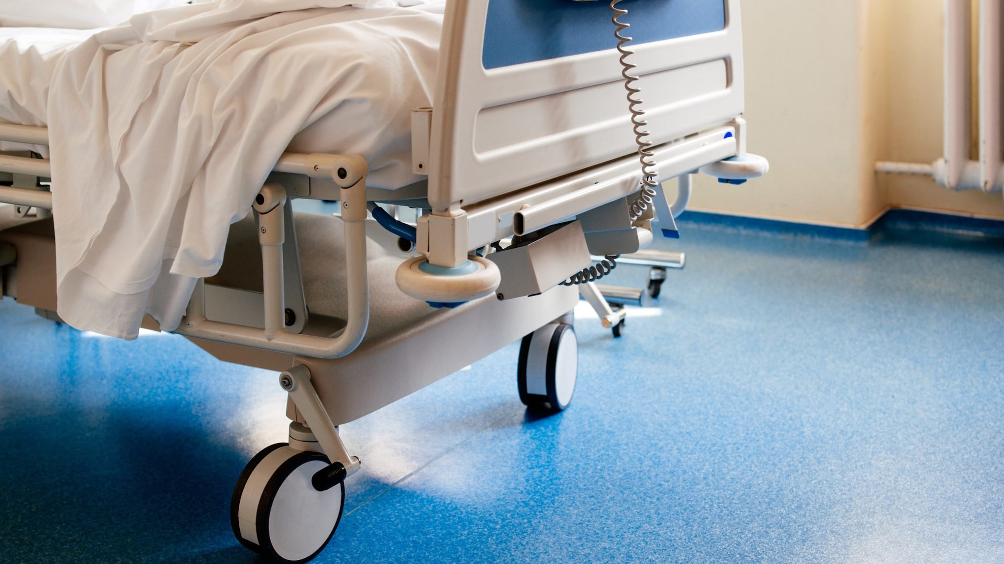 hospital bed with wheels on a blue floor