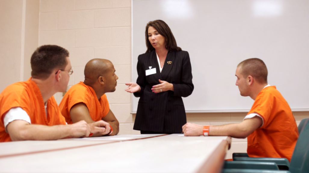 Correctional worker speaking to three people who are incarcerated.