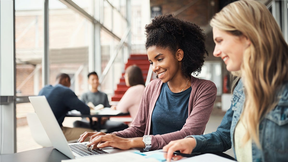 Two college students studying together over a laptop