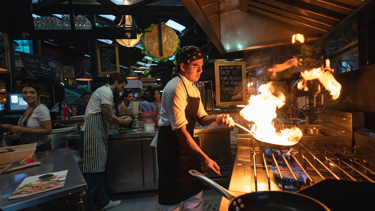 Chef cocinando en un restaurante flambeando la comida