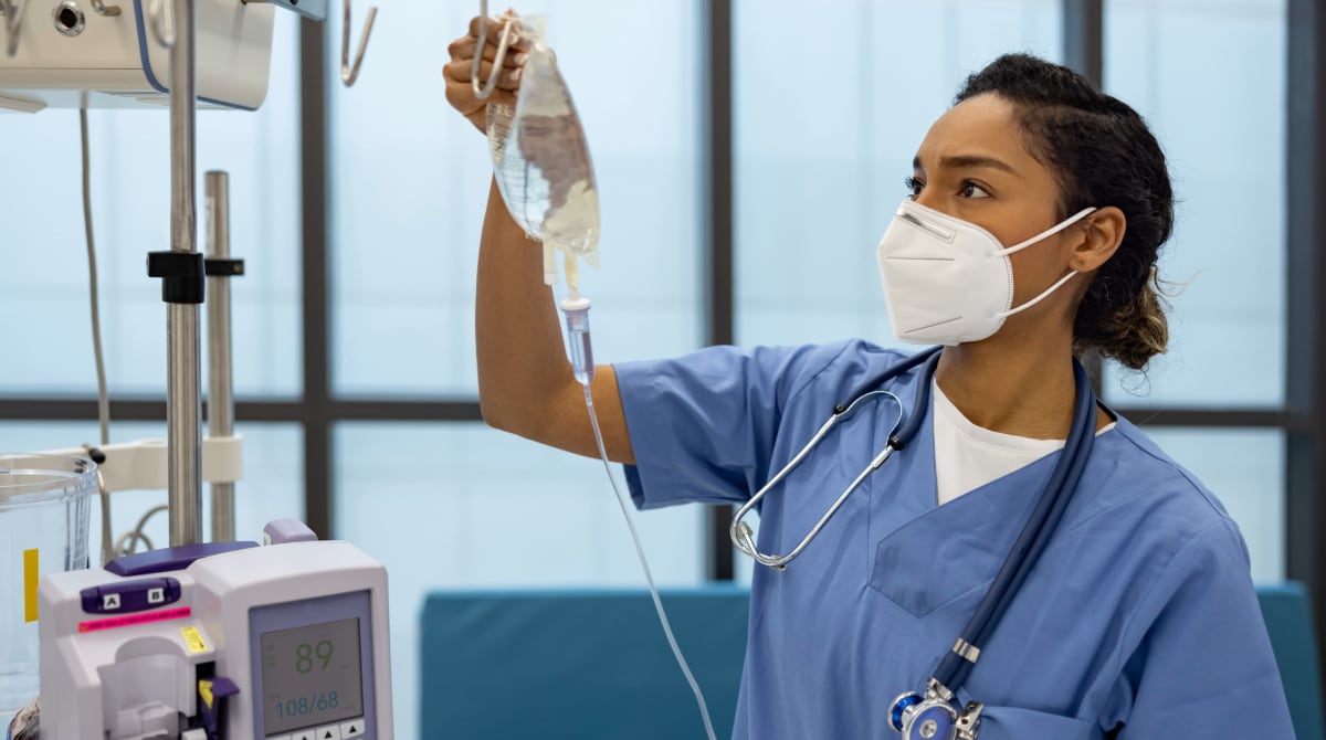 Una enfermera en el hospital poniéndole un suero a un paciente.