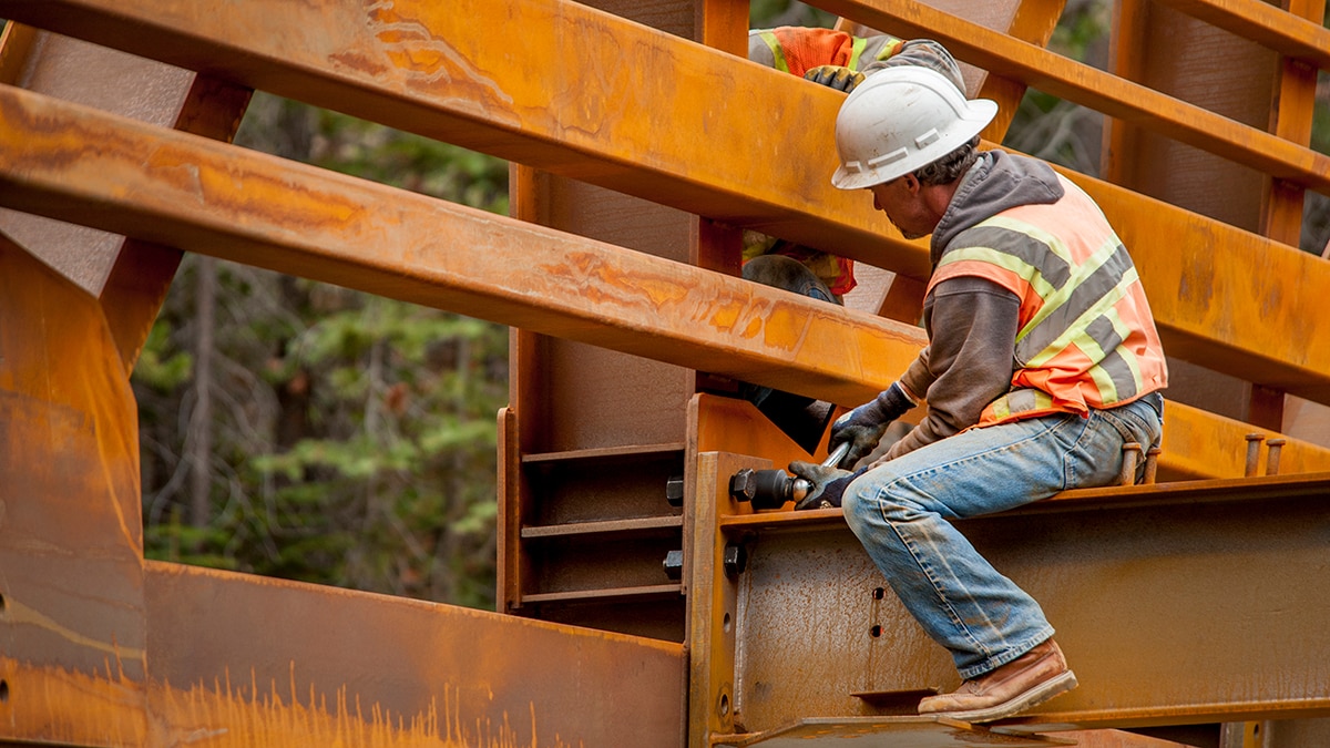 Steel workers on a bridge in the woods