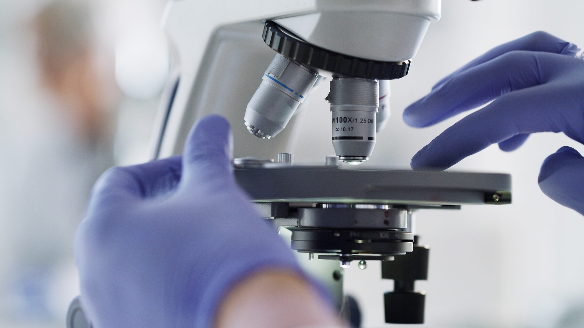 hands with gloves adjusting a microscope