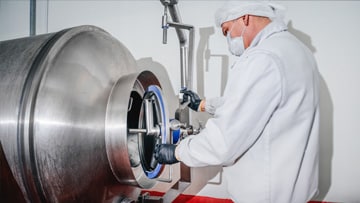 Scientist wearing a white lab coat working on a manufacturing tumbler