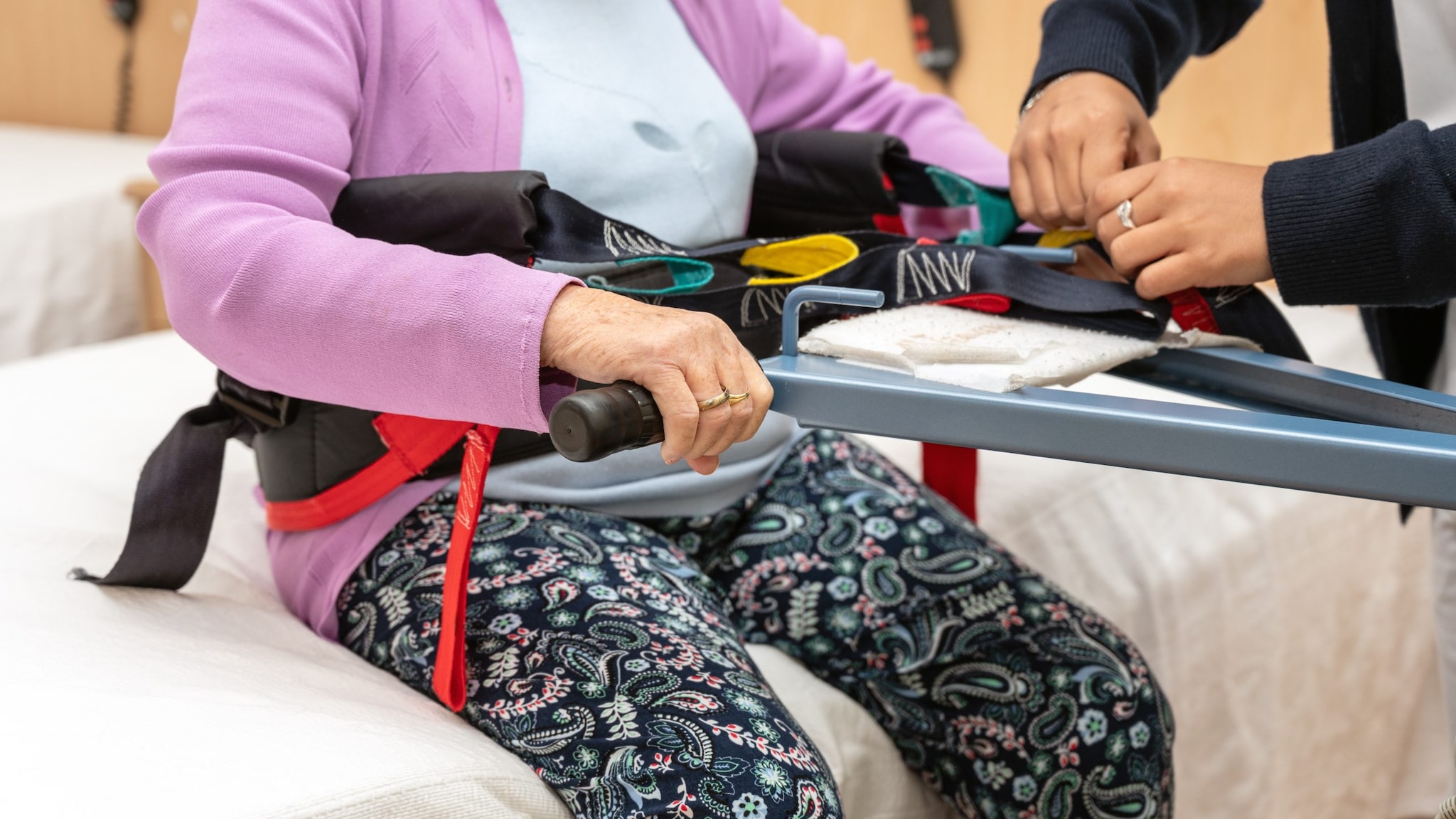 Nurse using a power assist to lift patient.