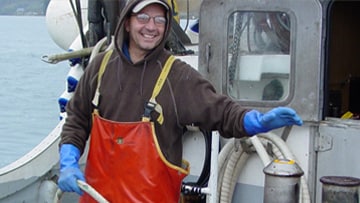 A fisherman simulates the activation of the winch-mounted emergency stop system on the deck of the salmon purse seiner. Photo by NIOSH