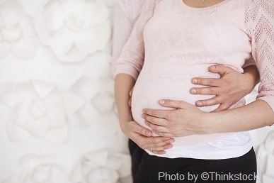 A pregnant woman places her hands on her belly