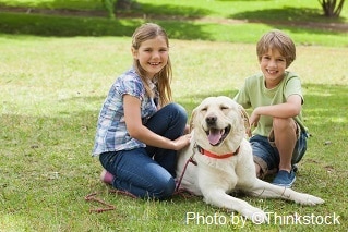 Two happy children lying next to a pet dog