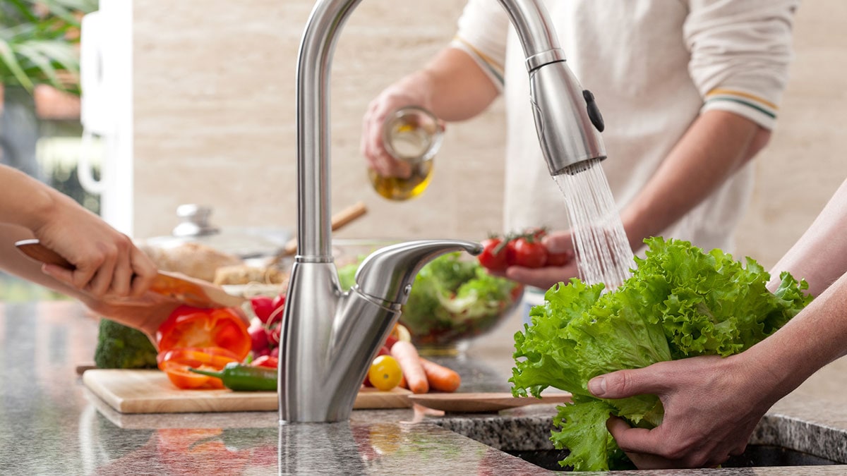 Close up picture of hands washing lettuce at the sink and hands chopping ve