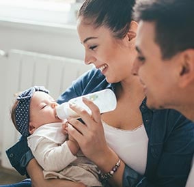 A parents feeding their baby from a bottle.