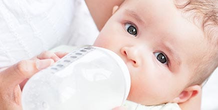 Mom feeding her baby formula from a bottle.