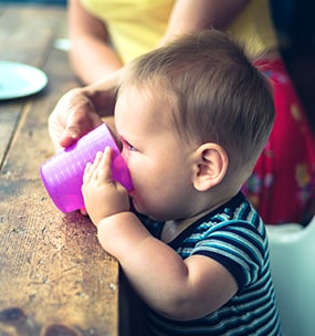 An older infant drinking from a cup.