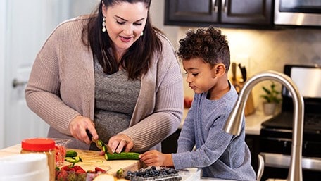 Mother and son preparing vegetables in home kitchen.