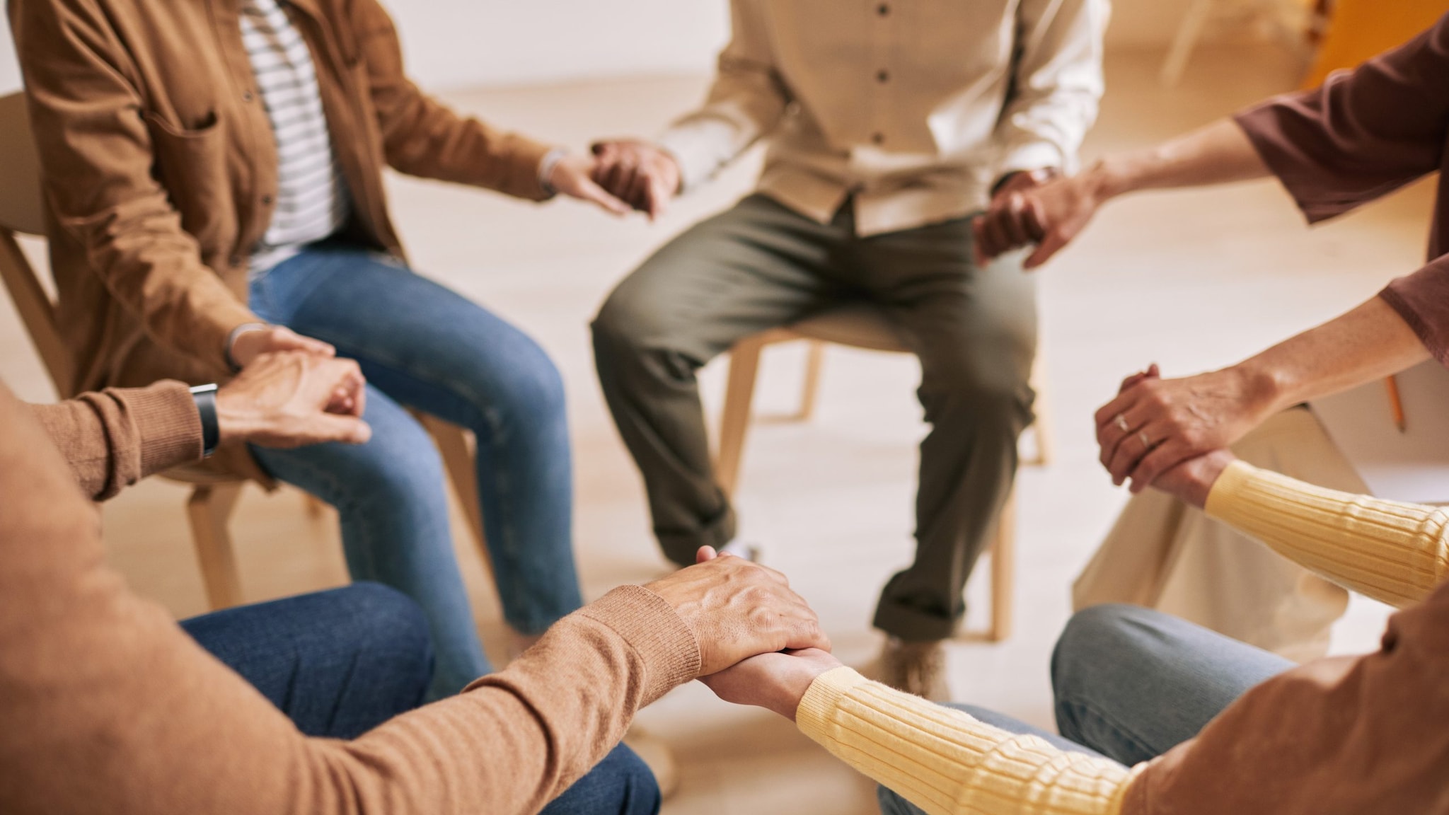 A group of people sitting in a circle and holding hands.