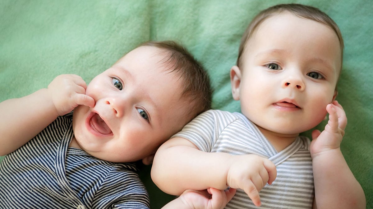 Newborn twins boys are lying on the bed