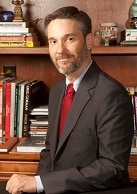 A photograph of Dr Samuel F. Posner appears behind a desk in front of a bookshelf.