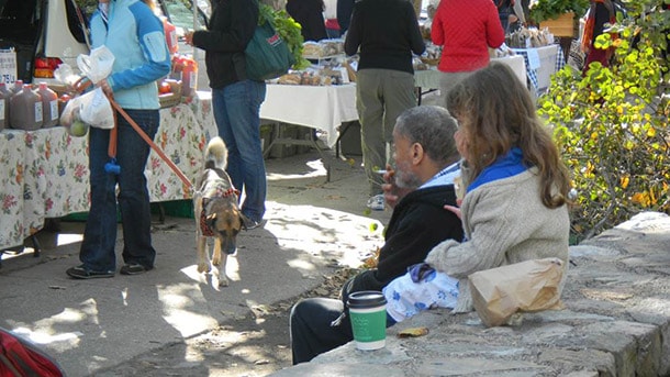 Man sitting outdoors smoking a cigarette while a child behind him covers her mouth and nose