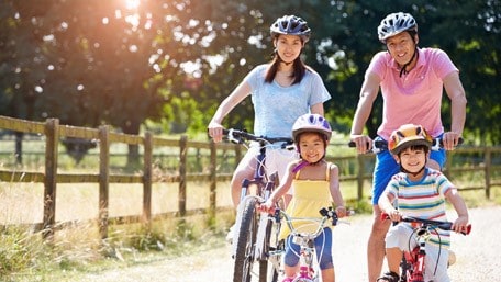 Family of four riding bikes outside.