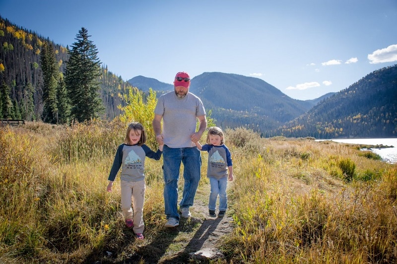 Man and two children walking outdoors and holding hands.