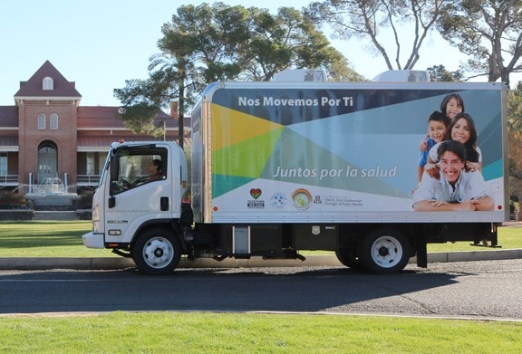 Image of a truck with a family shown on the side. The truck in stopped or parked in front of a brick building.