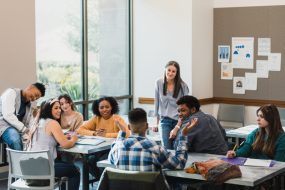 Teen students listen to peer in a classroom