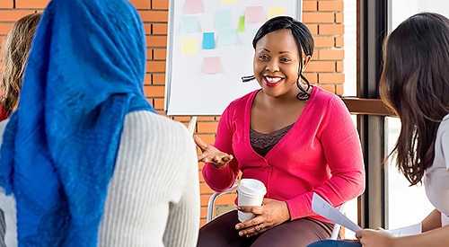 Black woman leading casual conference meeting.