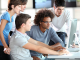 Four people viewing a desktop screen