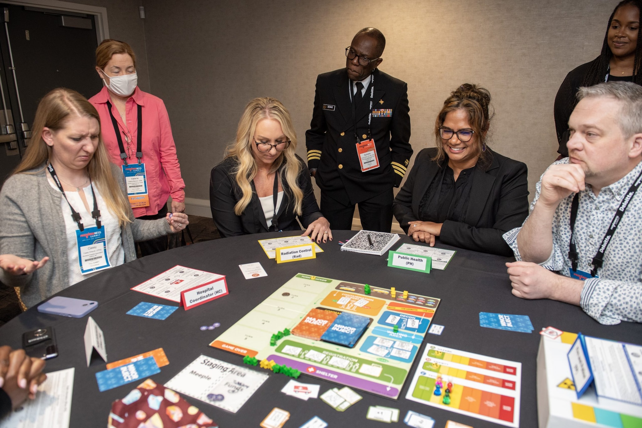 Group of people with gameboard and pieces on table.