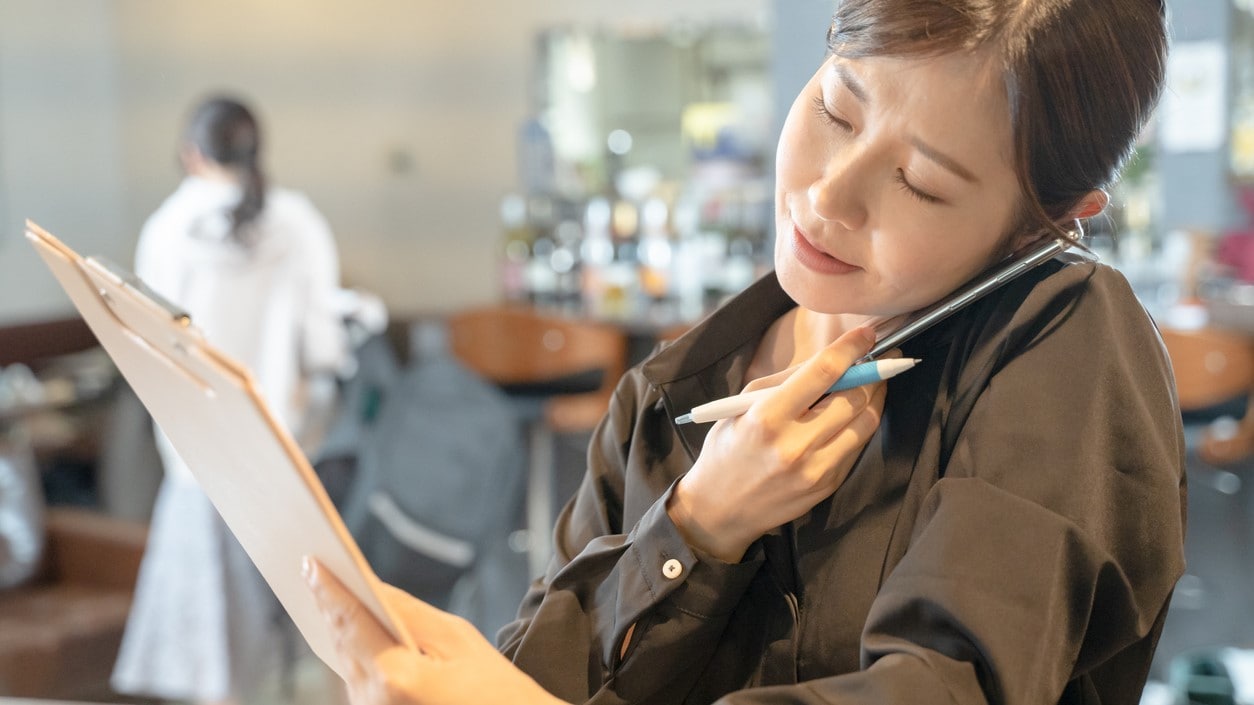 Restaurant manager on the phone with a pen and folder.