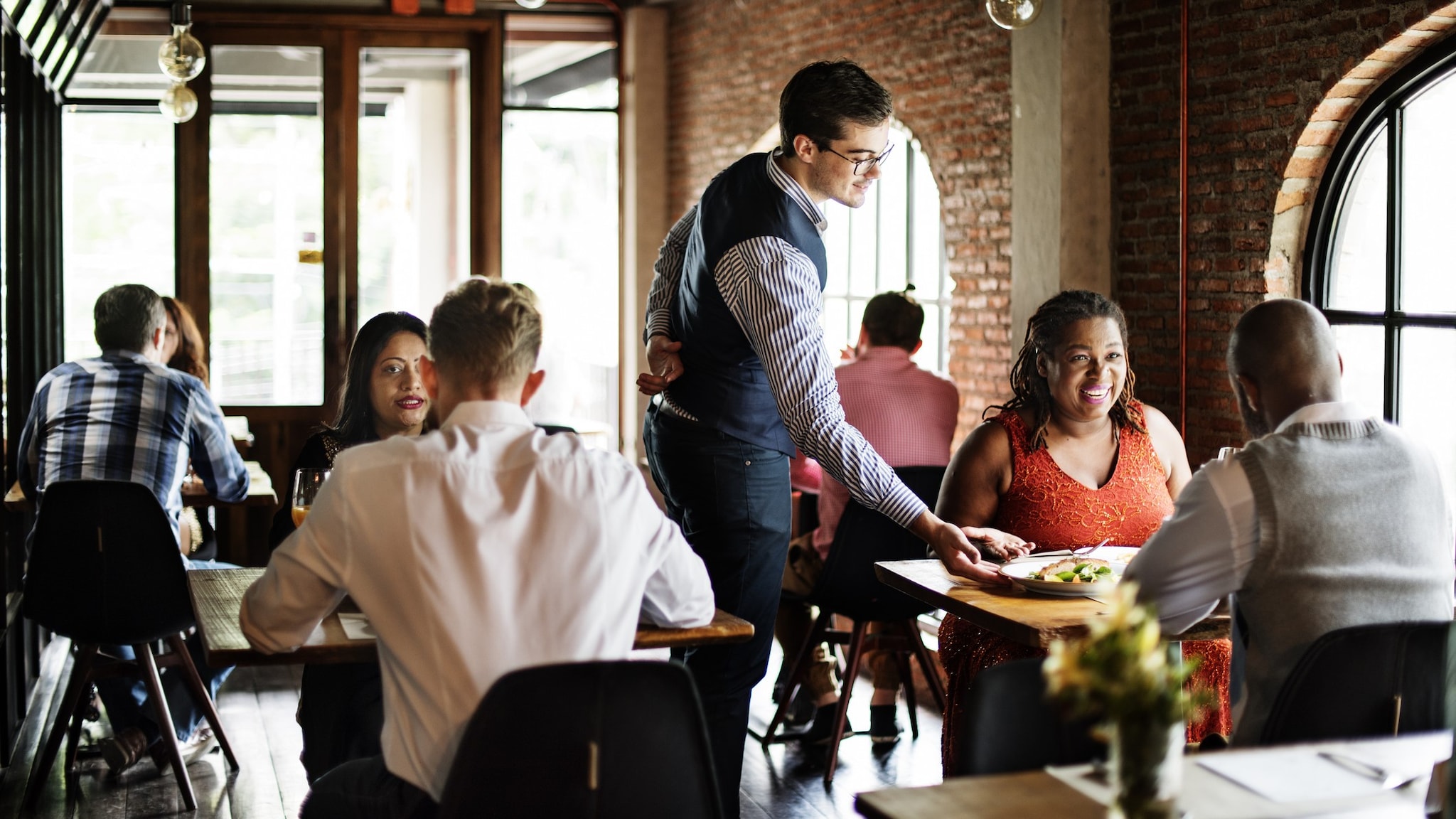 Wide shot of a restaurant with several people at different tables.