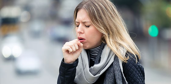 Woman cough while walking through city street