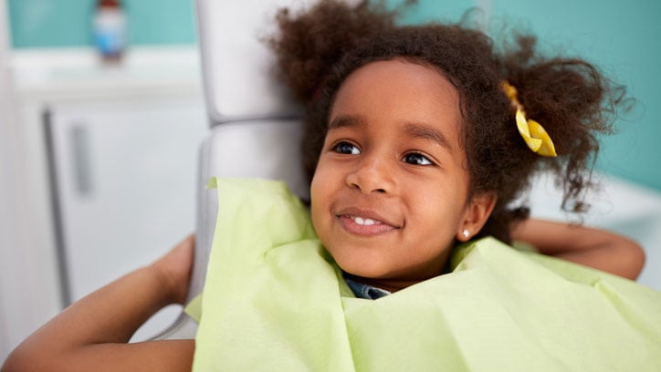 A young girl smiling in dentist chair.