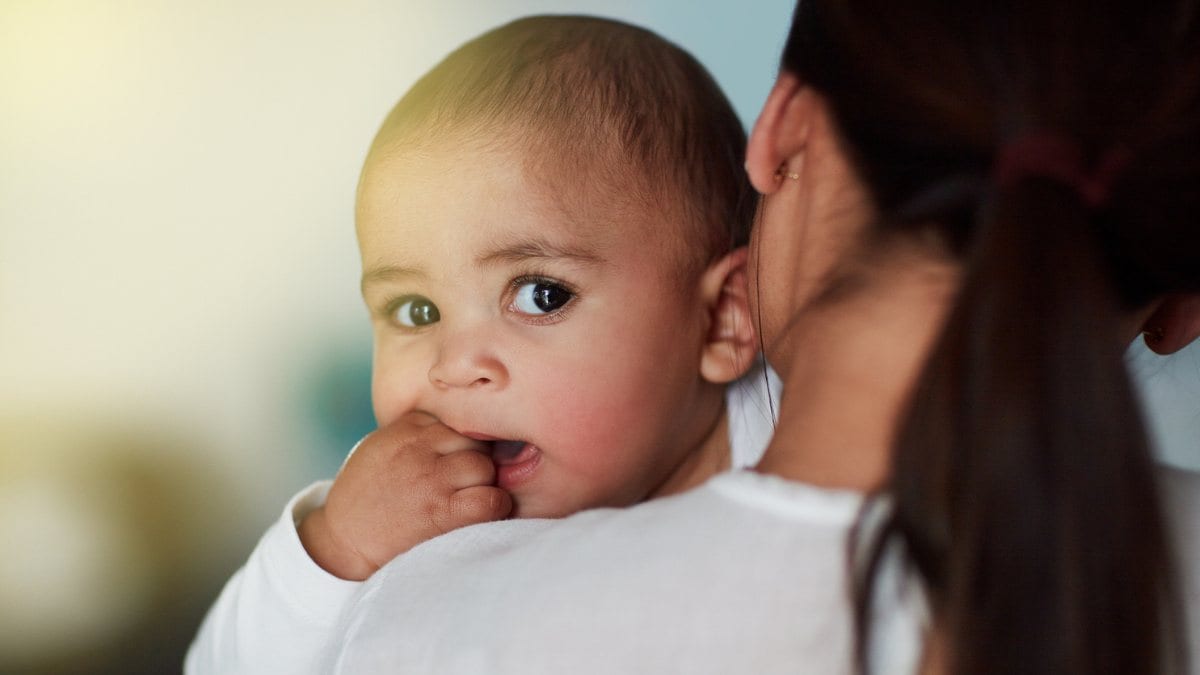 Baby peeking over the shoulder of its parent