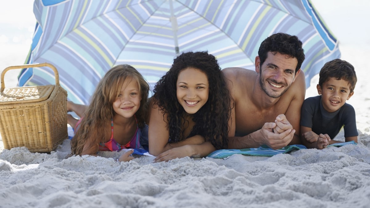 una familia bajo una gran sombrilla en la playa