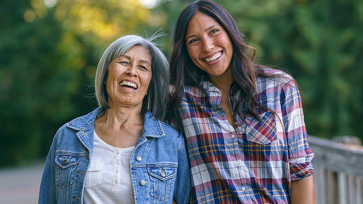 Mother and daughter smiling outdoors.