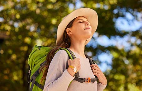 Una mujer de excursión en el bosque inhala profundamente.