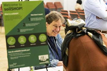 Una persona trabajando en una mesa de información en un evento de soilSHOP.