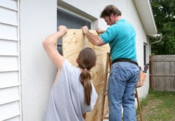 Hombres cubriendo ventanas con tablas