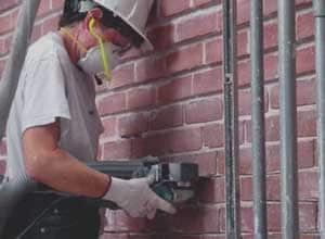 Trabajador utilizando un pulverizador para quitar el mortero.