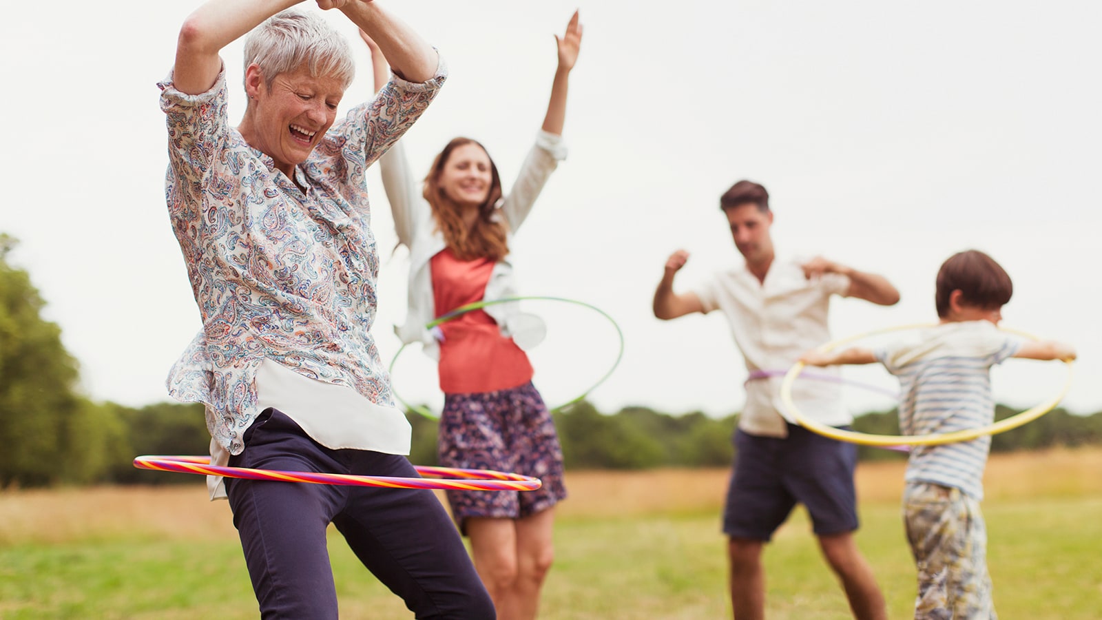 Playful multi-generation family playing with hula hoops outside.