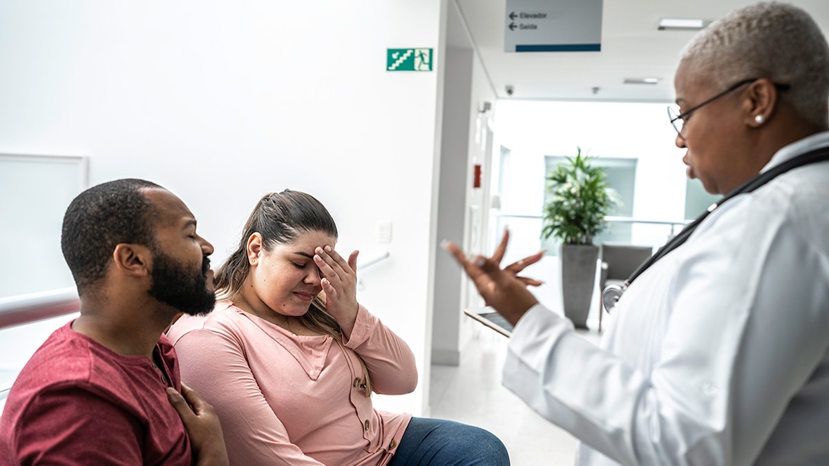 Female doctor talking to grieving couple in a hospital