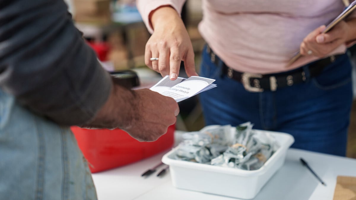 A syringe services program (SSP) worker offers a health services pamphlet.