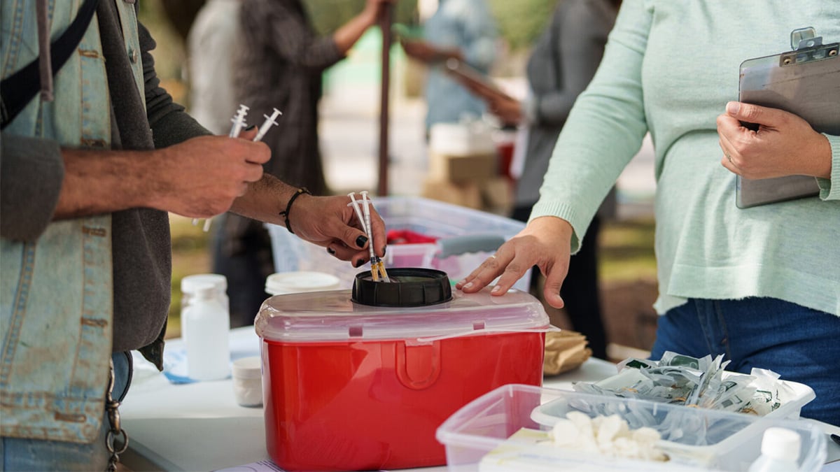 A man disposes used syringes at a syringe services program (SSP) site.