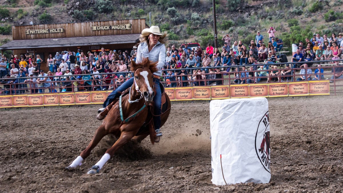 Photo of a woman riding her horse on a rodeo.