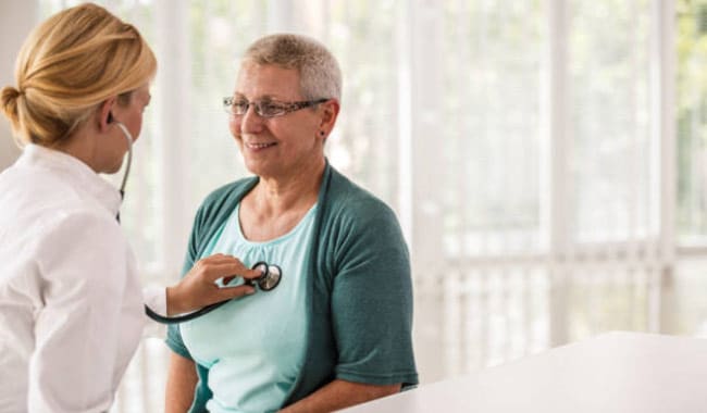 Doctora escuchando los latidos del corazón de la paciente