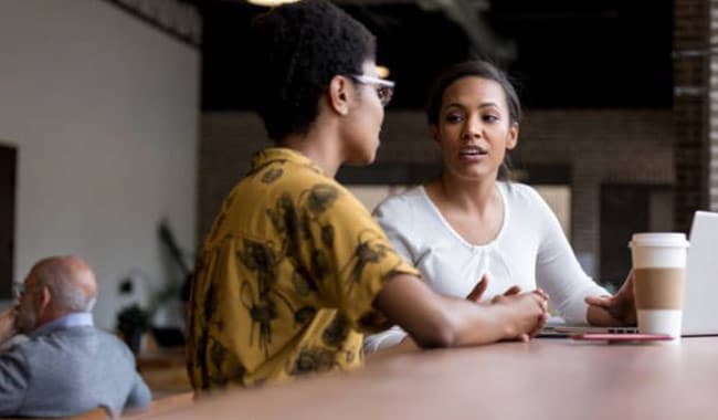 Dos mujeres jóvenes, hablar, en, cafetería