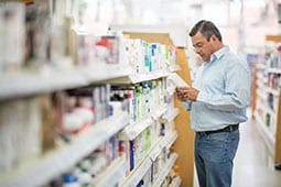 Hombre en farmacia buscando medicamentos para dejar de fumar.