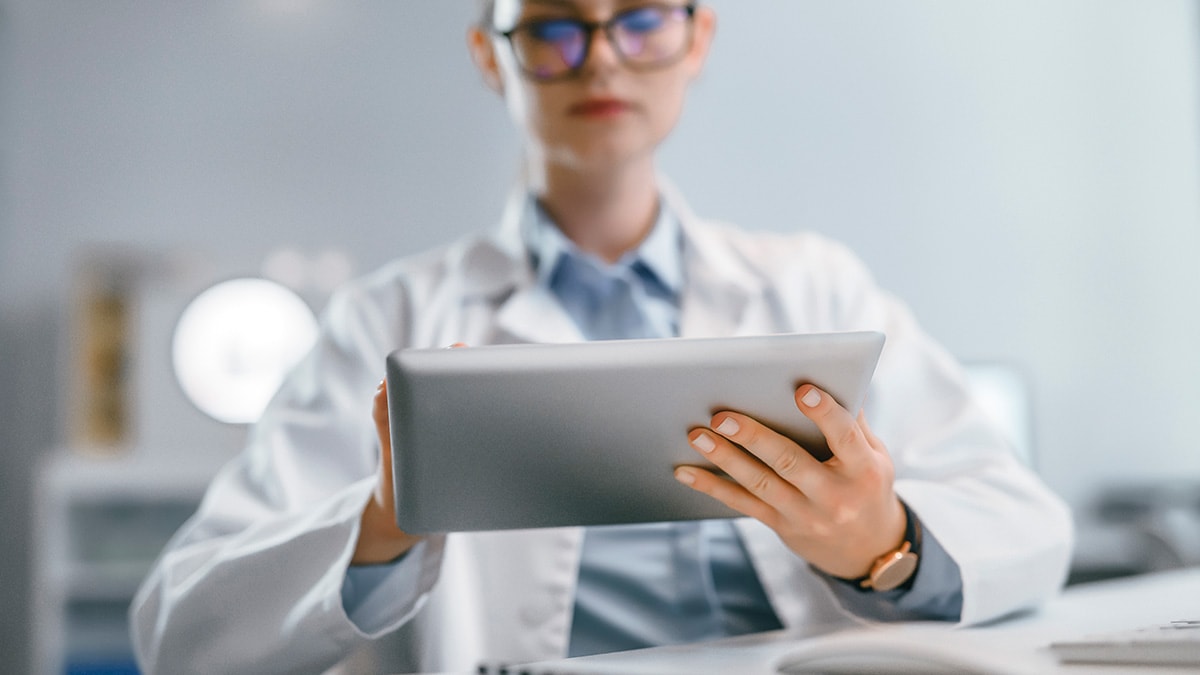 Researcher in a lab coat using a tablet