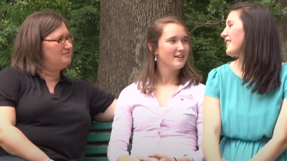 Tres mujeres sentadas en un banco en un parque hablando sobre el síndrome de Gilles de la Tourette