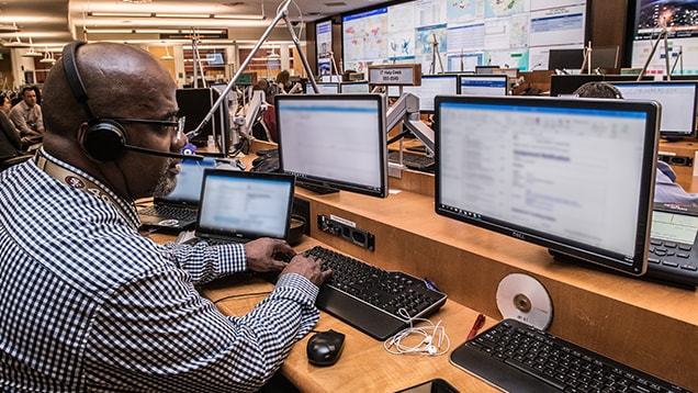 Man typing on computer in emergency operations center.